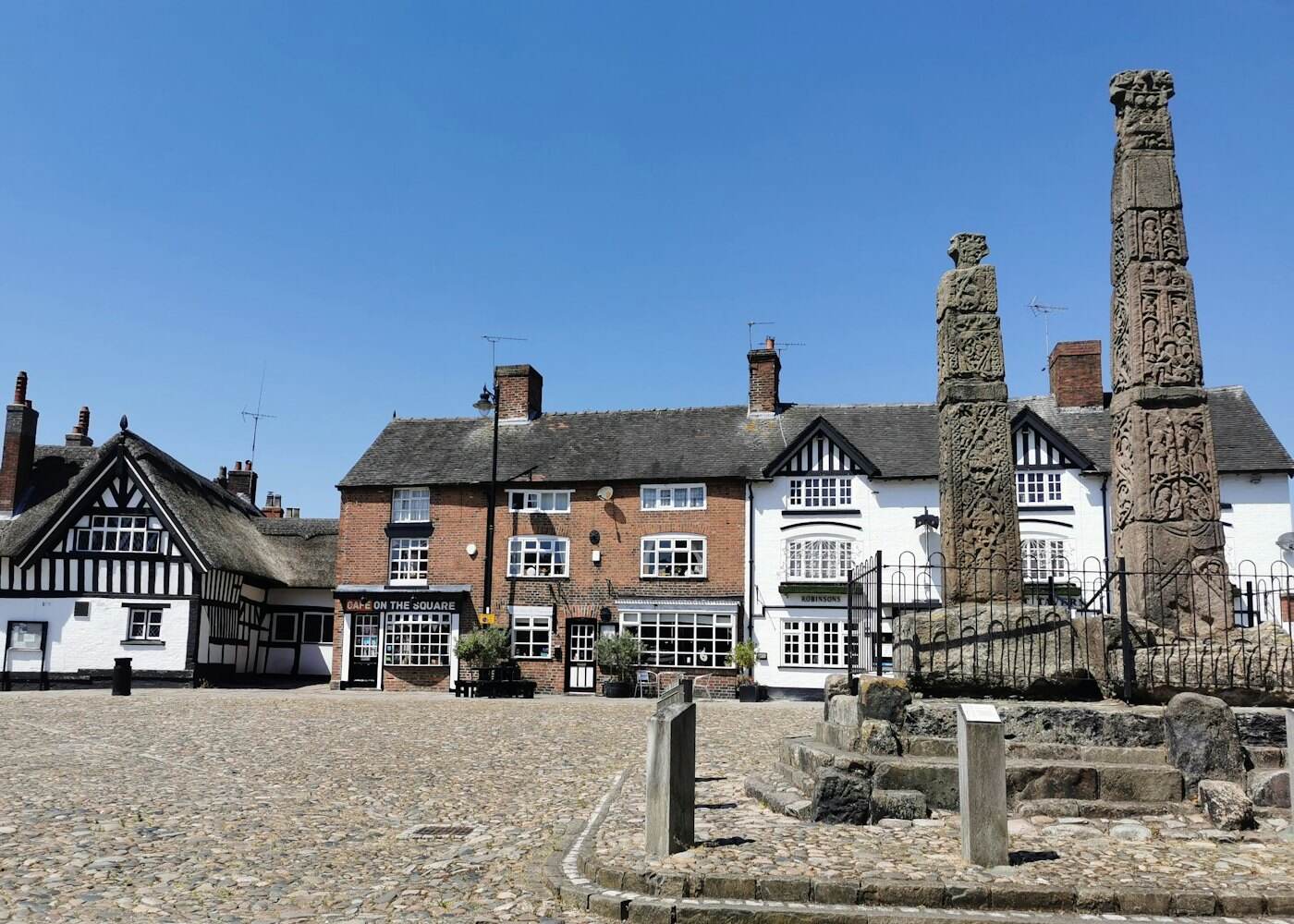 A Cheshire village square with timbered buildings and a market cross